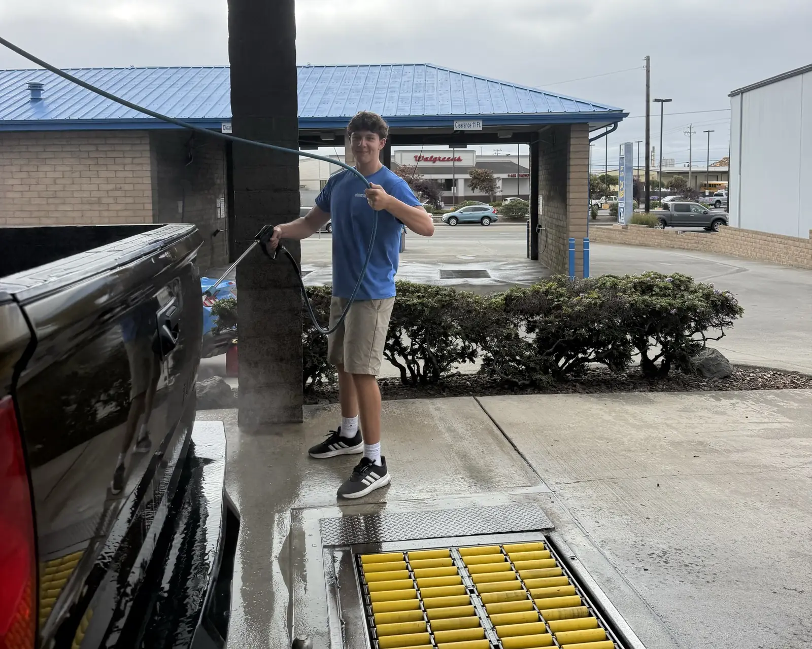 A Zenith crew member pre-washing a truck by hand with a pressure wand at the tunnel entrance