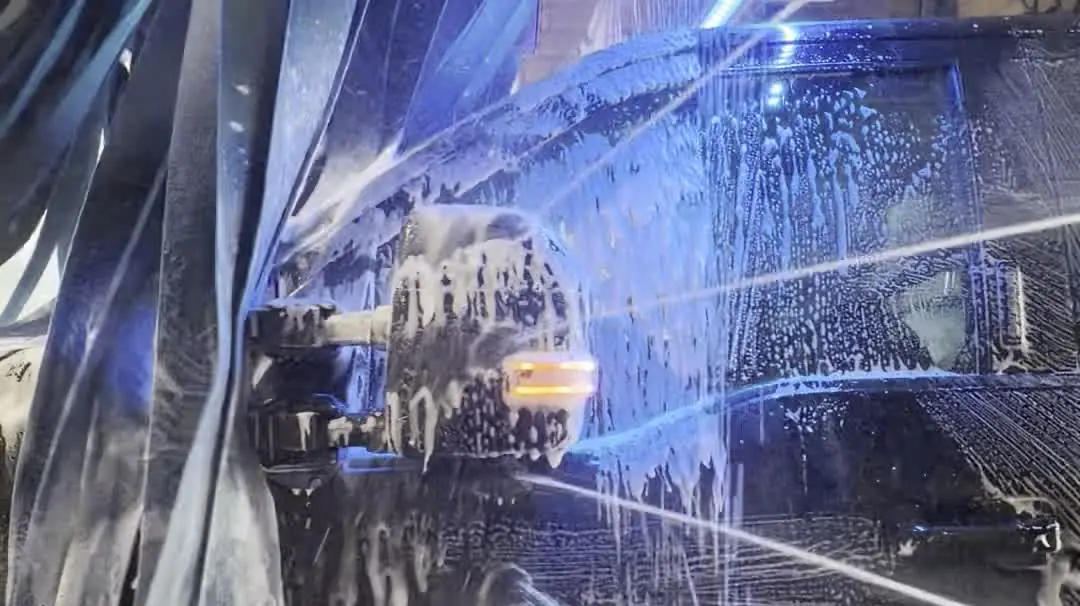 Soap and soft cloth across a car window inside the wash tunnel at Zenith Car Wash